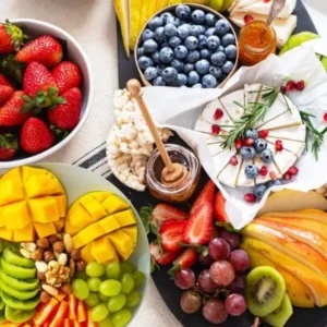 Fresh fruit, cheese, nuts, and honey artfully arranged on a table for a colorful display.