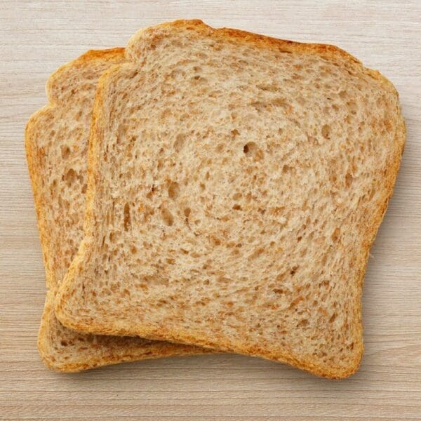 Two slices of light brown whole wheat bread on a wooden surface.