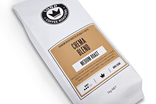 White bag labeled "Lund Coffee Roasters" with Crema Blend, Medium Roast, 1kg, flavor details.