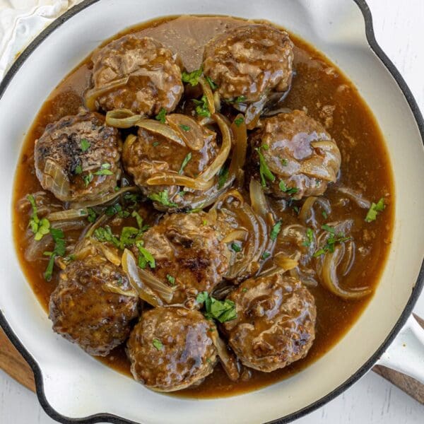 STEAKETTE RISSOLES Glazed meatballs with herbs, pineapple, and sesame seeds in a rich sauce served in a bowl.