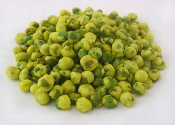 Pile of greenish wasabi-coated peas on a white surface.