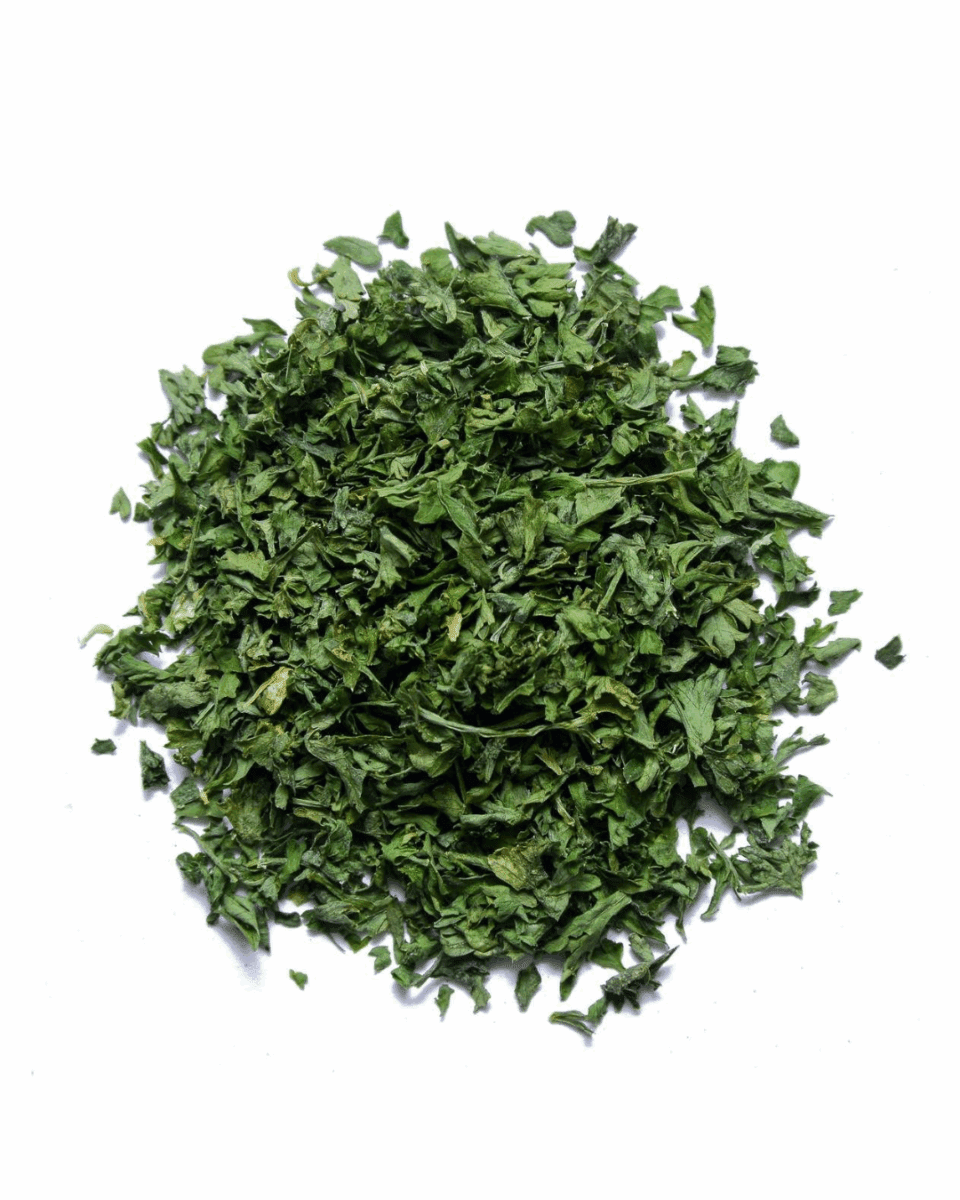 Pile of finely chopped green dried herbs on a white background.