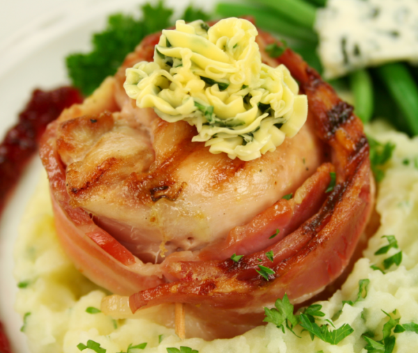 Bacon-Wrapped Chicken with Herb Butter on Mash Chicken wrapped in bacon with herb butter on mashed potatoes, green beans, cheese, cranberry.