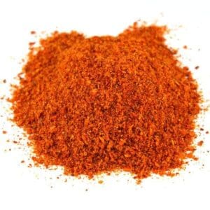 Small pile of coarse red-orange ground spice on white background.