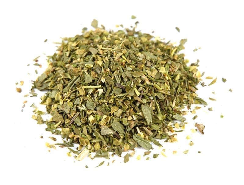Pile of dried mixed herbs with green and brown leaves in varied sizes and coarse texture.