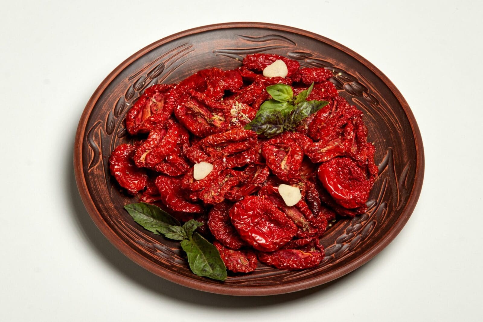 Rustic plate with sun-dried tomatoes, basil, and garlic on a decorative dish.