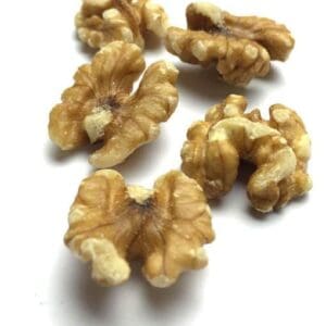 Shelled walnut halves on white surface, showing ridged and uneven textures.