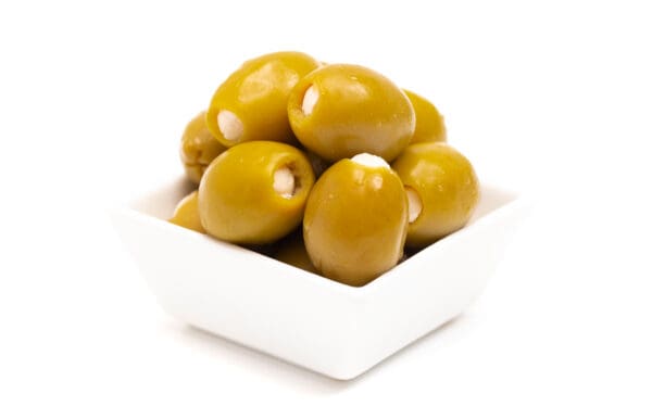 Small white bowl of green olives with cream-colored stuffing, on a plain white background.