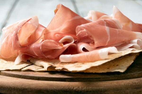 SAN NICOLA PROSCIUTTO Thinly sliced prosciutto with marbling in pink and white tones.