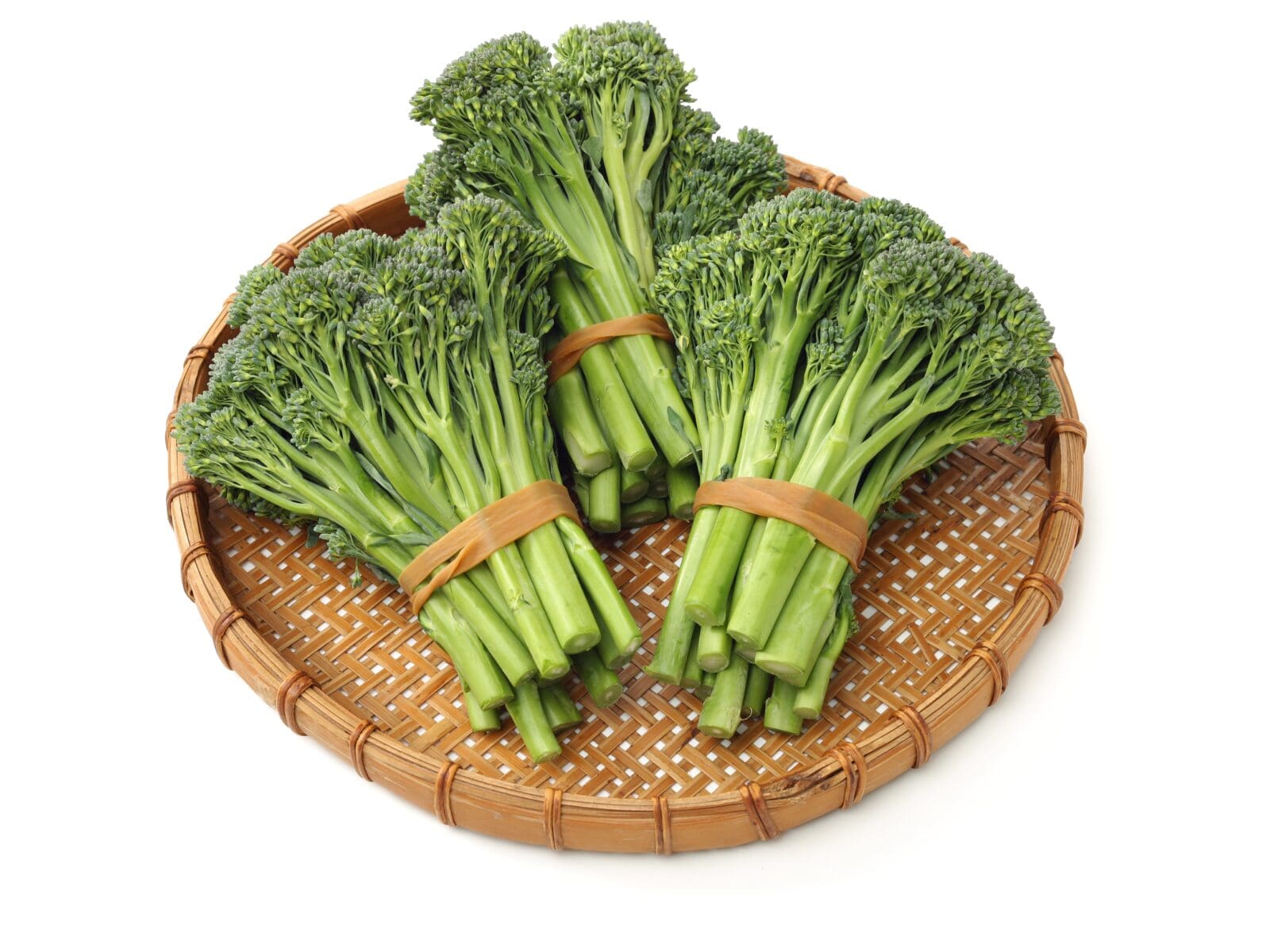 Woven bamboo tray with fresh broccolini bundles, dark green stalks and florets secured with bands.