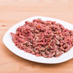 Plate with minced meat and vegetables on wooden table