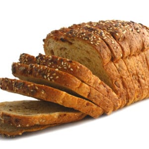 Sliced multigrain bread loaf with seed-topped crust on display.