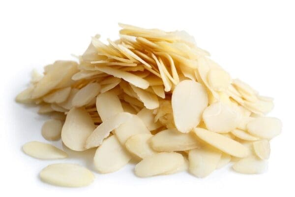 Thinly sliced almonds piled on a white surface, showing creamy color and smooth texture.