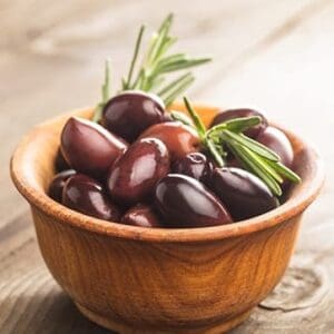 Wooden bowl with dark olives and rosemary on a wooden surface.