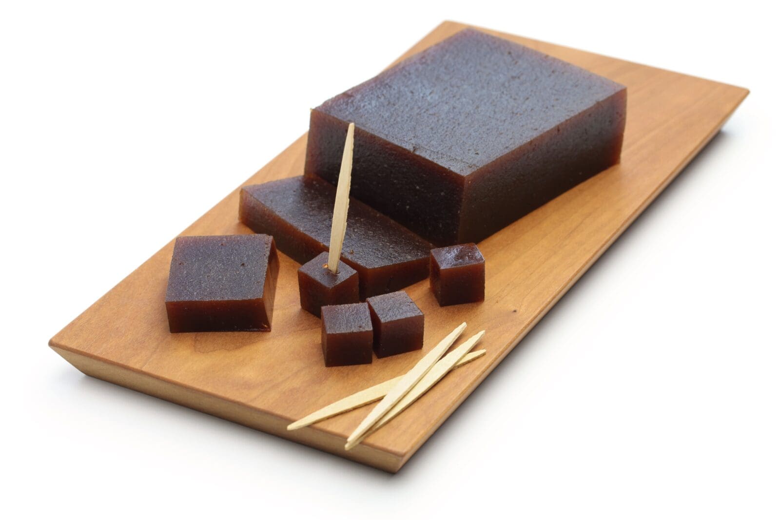 Wooden tray with dark jelly block, cut into cubes with toothpicks inserted.